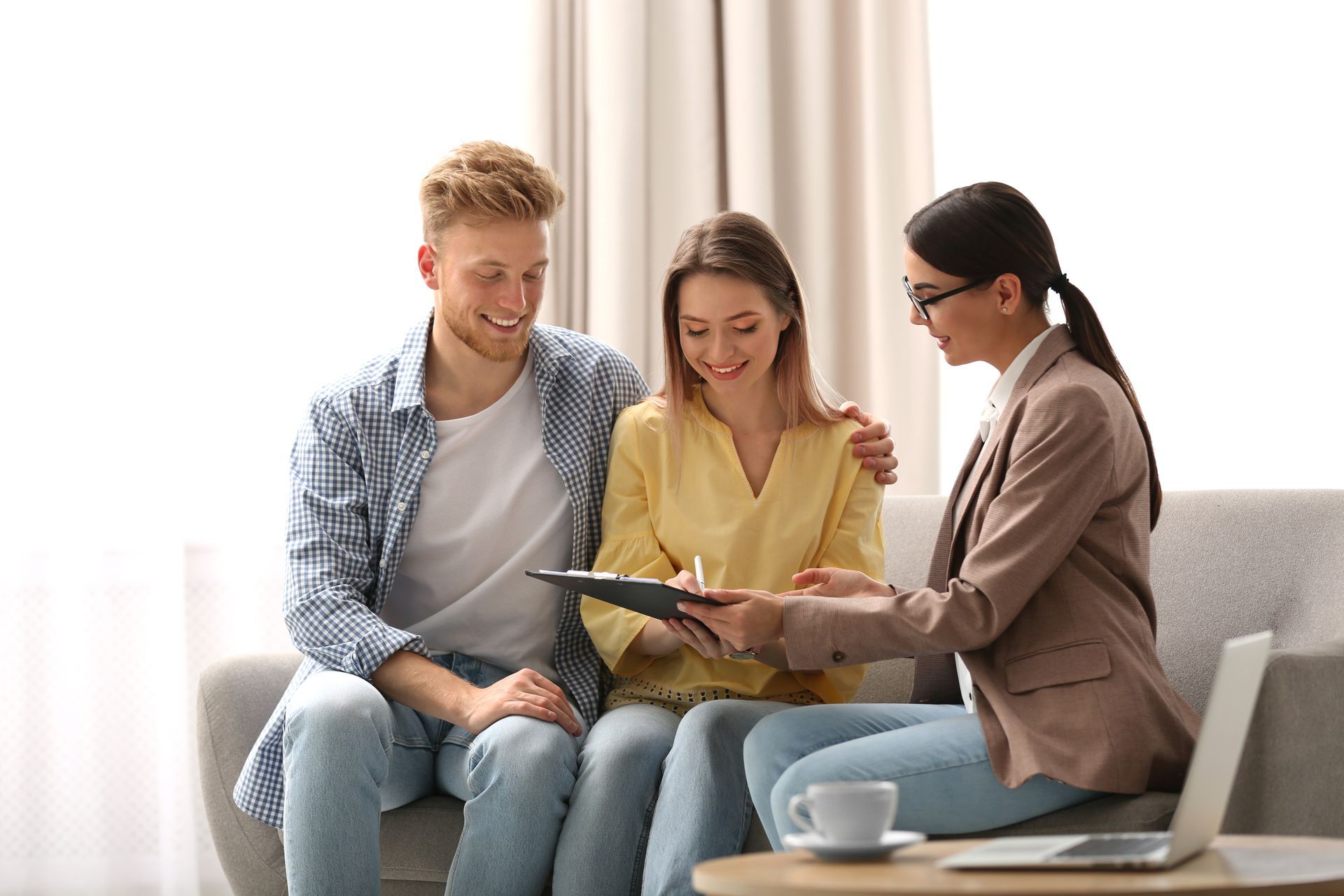 Three people on a couch reviewing a tablet together in a bright living room