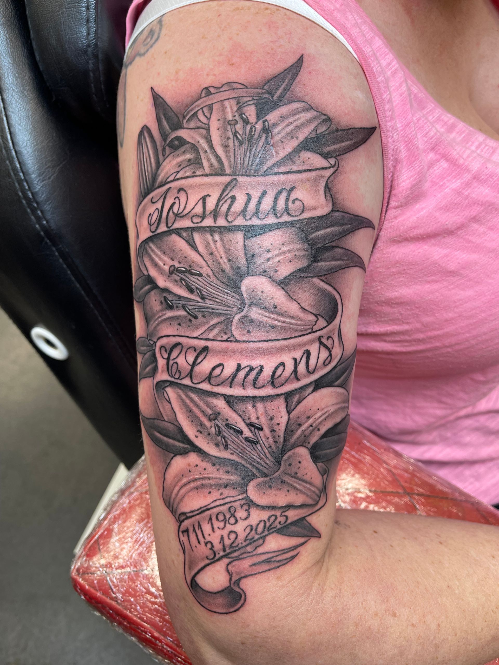 Arm tattoo with roses and script reading “Joshua Clements” on a bent arm