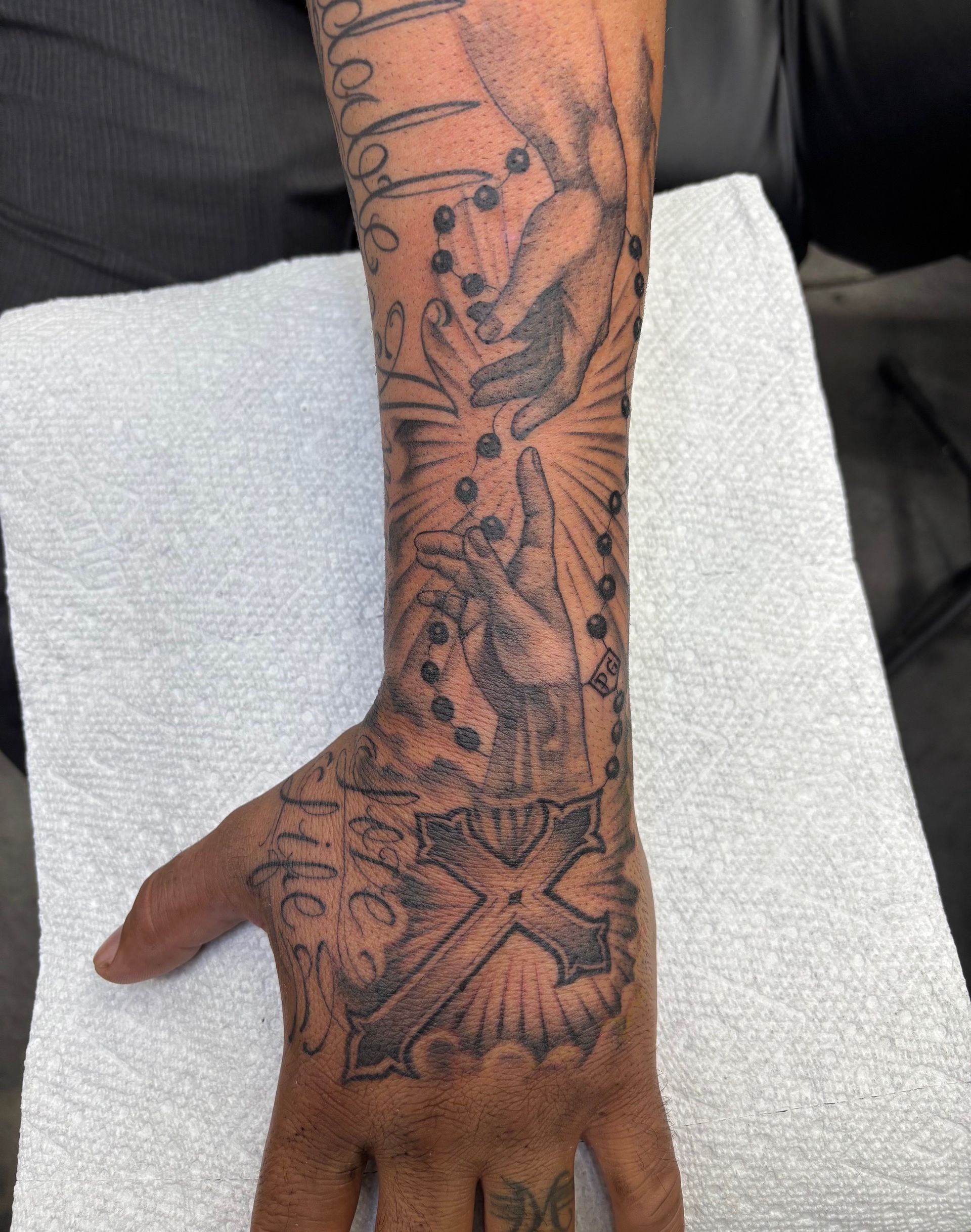 Forearm and hand with intricate black floral and butterfly tattoo on a dark skin tone