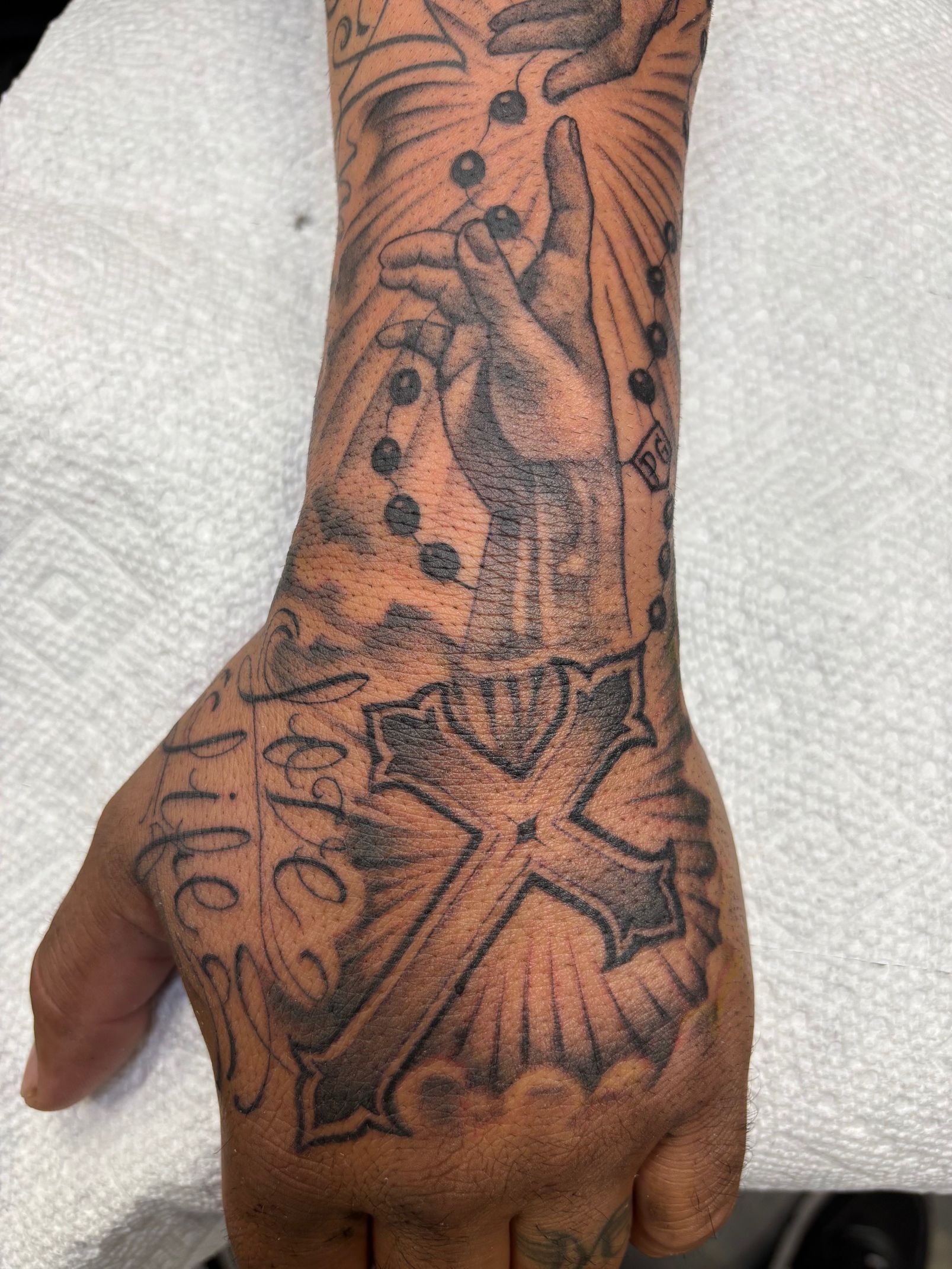 Close-up of a tattooed hand and wrist with a large star and floral design in black ink
