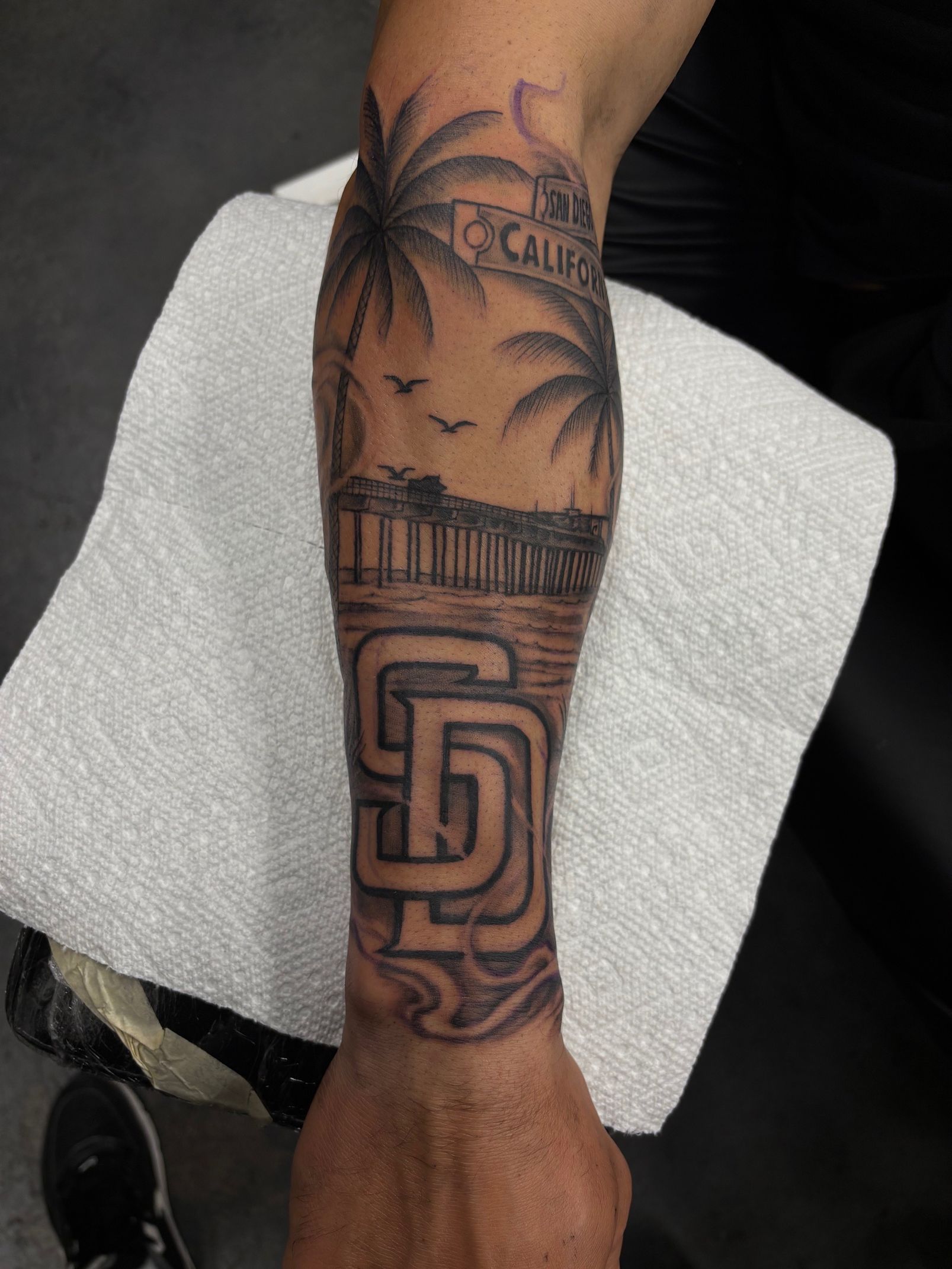 Forearm with intricate black tattoo resting on a rolled white towel