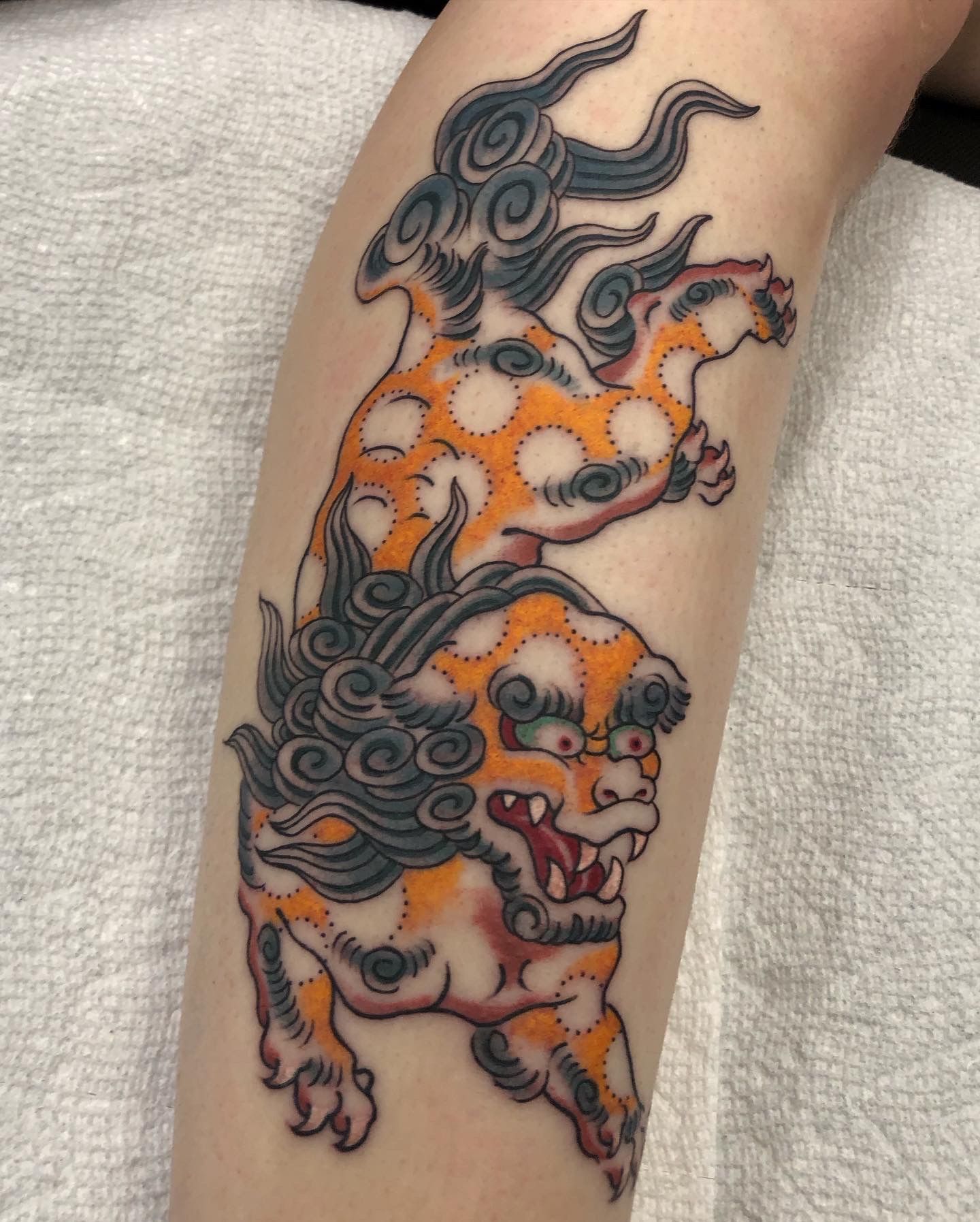 Black and orange tattoo of a stylized wolf on a forearm