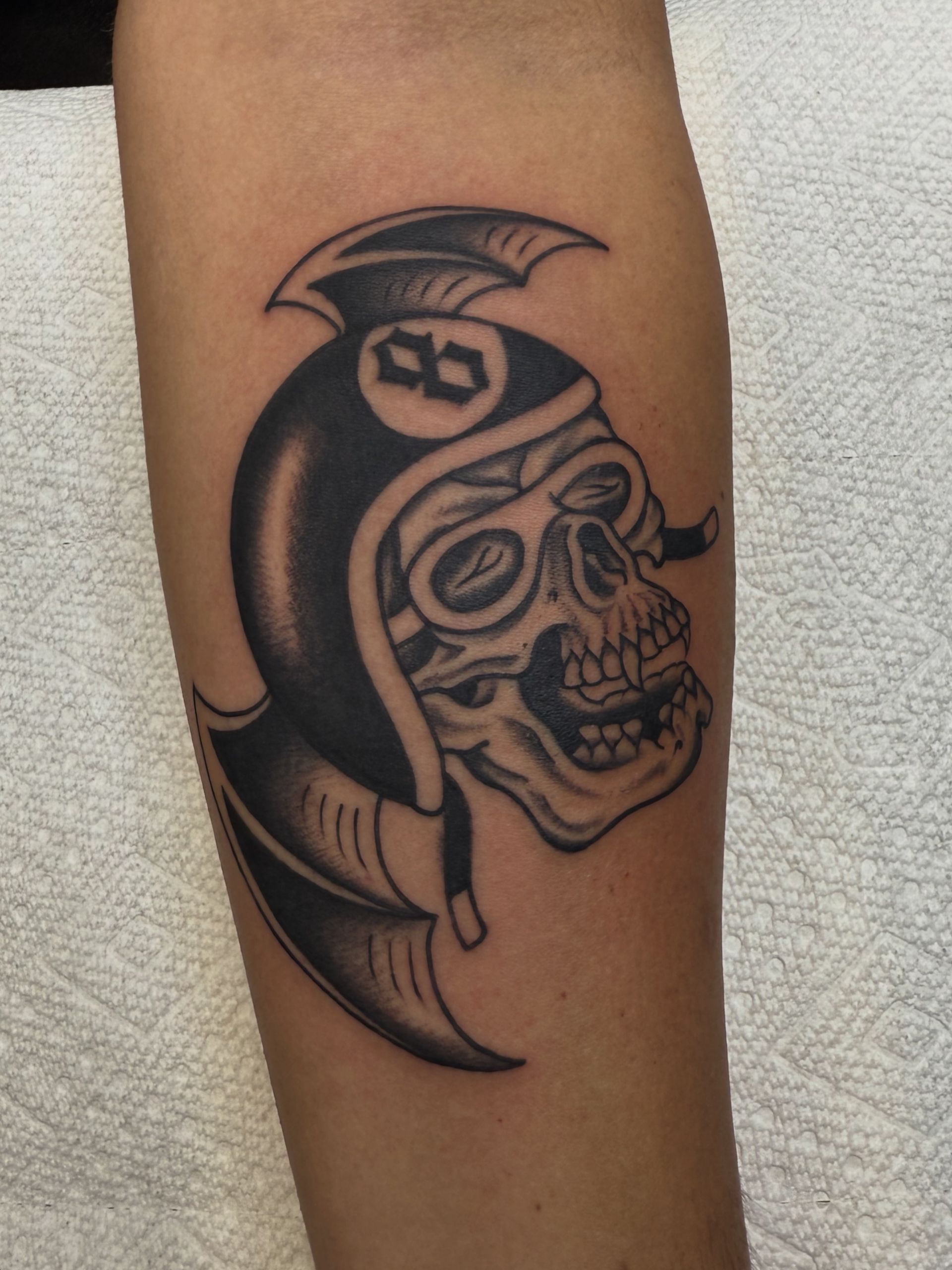 Black-and-gray skull tattoo with a Spartan helmet on an arm