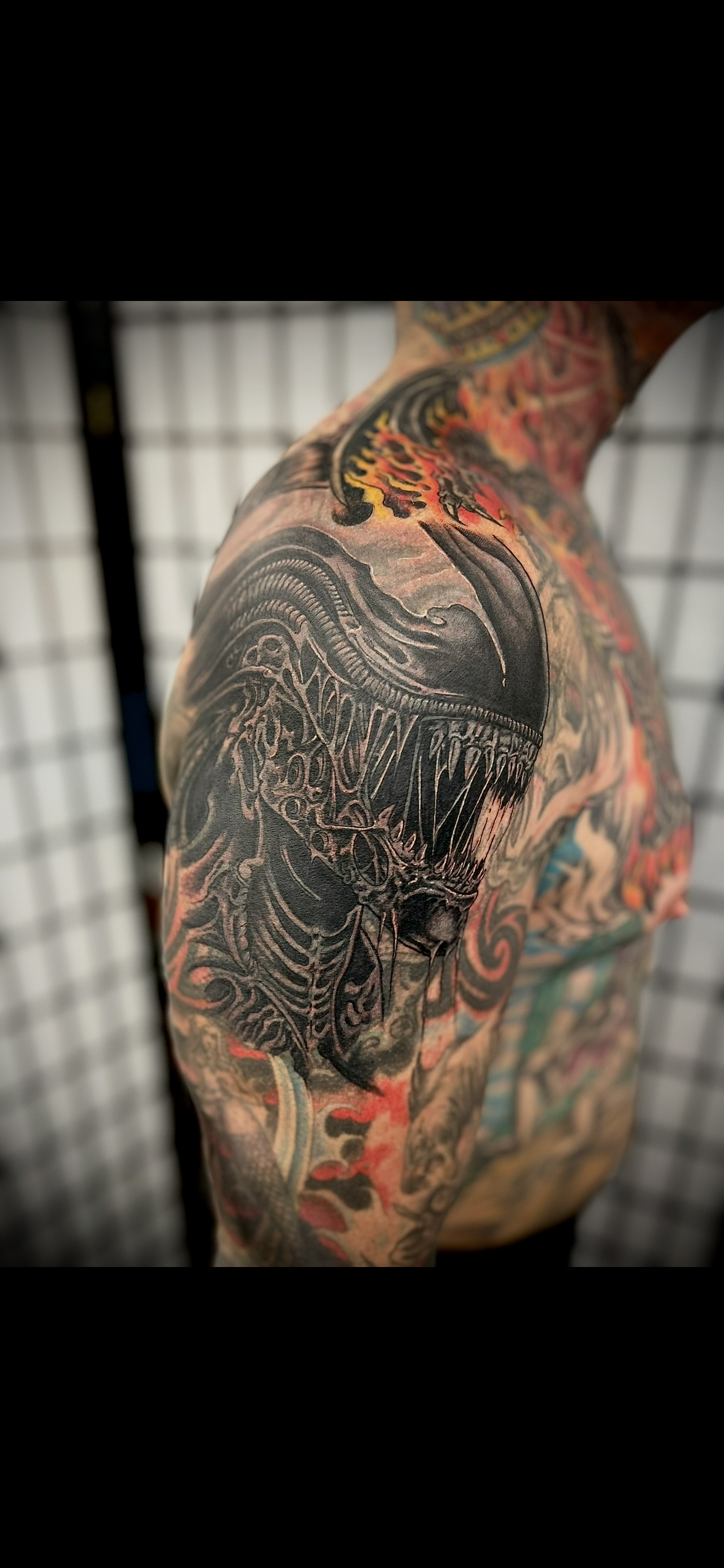 Close-up of a detailed black and red tattoo on an upper arm or shoulder area