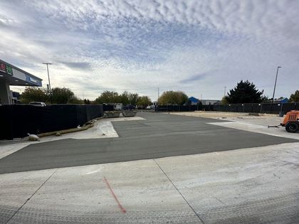 A concrete driveway is being built in front of a gas station.