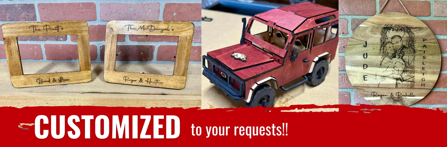 A red car is sitting on a wooden table next to a brick wall.