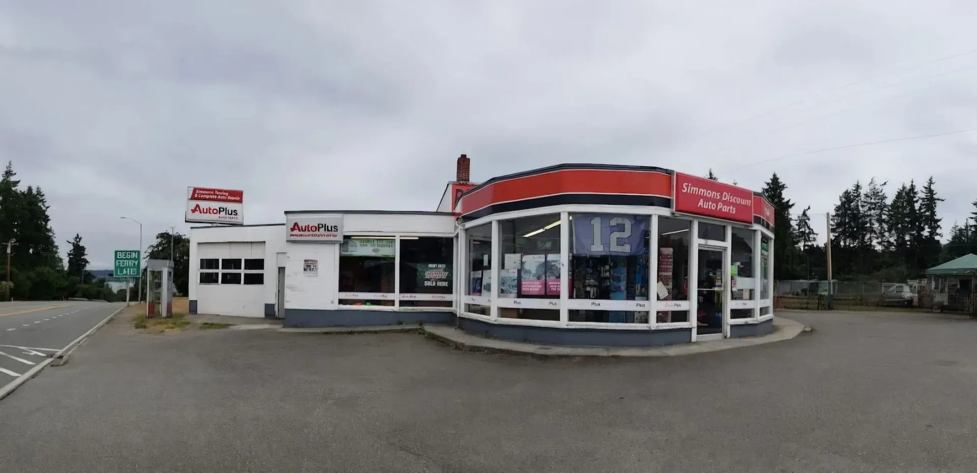 Small roadside convenience store with red trim and large windows on a cloudy day