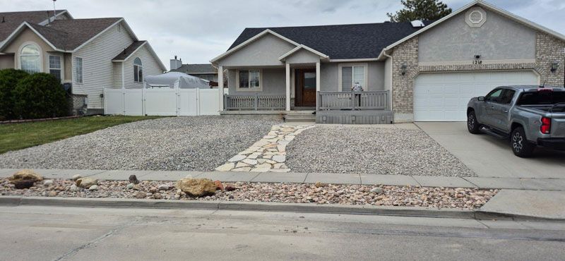 Suburban house with gravel front yard, stone walkway, and a car parked in the driveway.