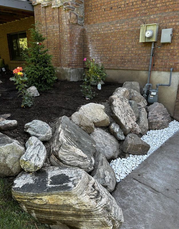 Rocks and boulders lining a garden bed beside a brick wall and concrete path