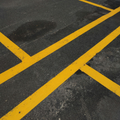 Yellow parking lot lines crossing on dark asphalt pavement