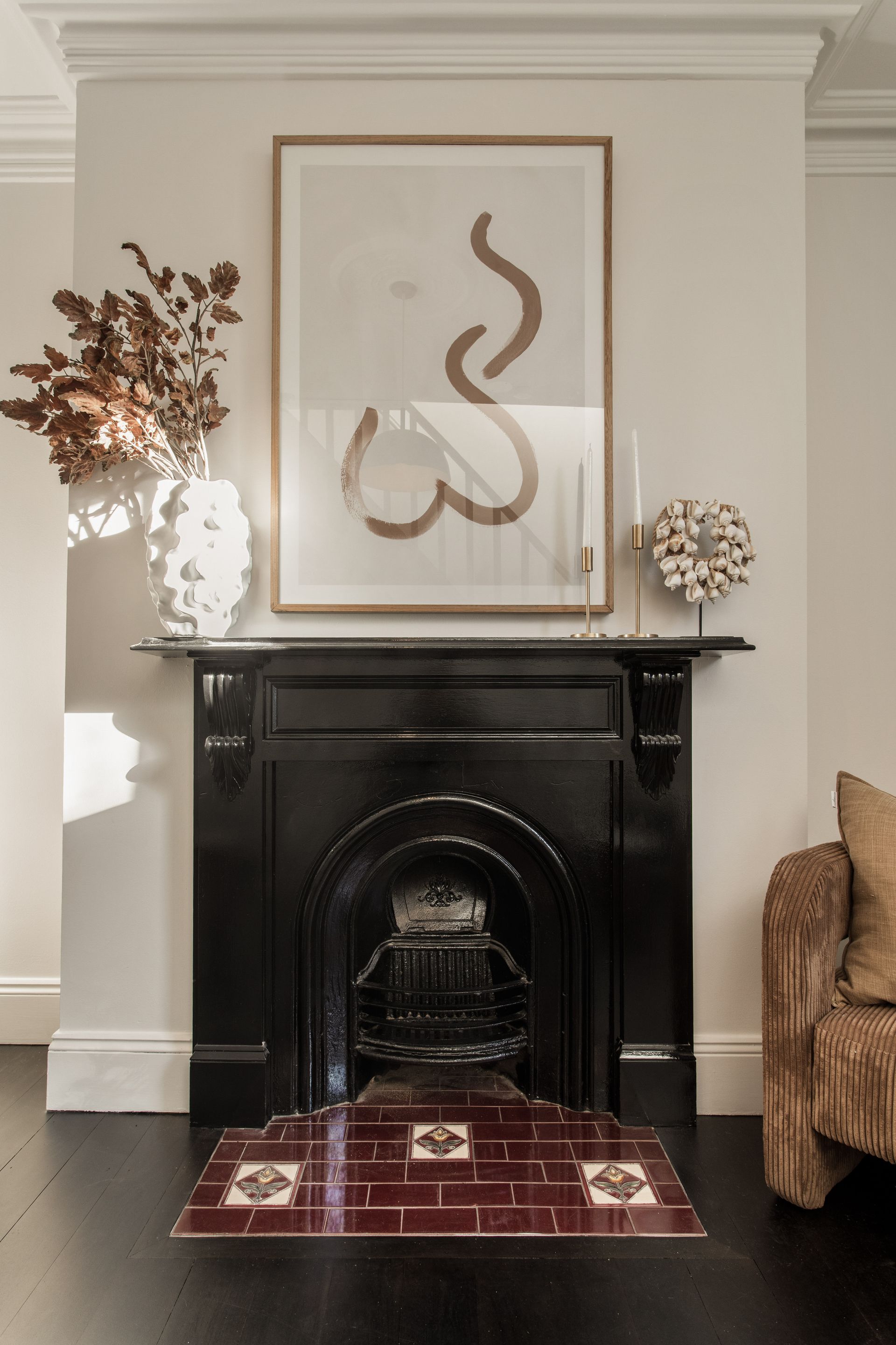 Elegant living room fireplace with black mantel, abstract art, and dried floral arrangements on either side
