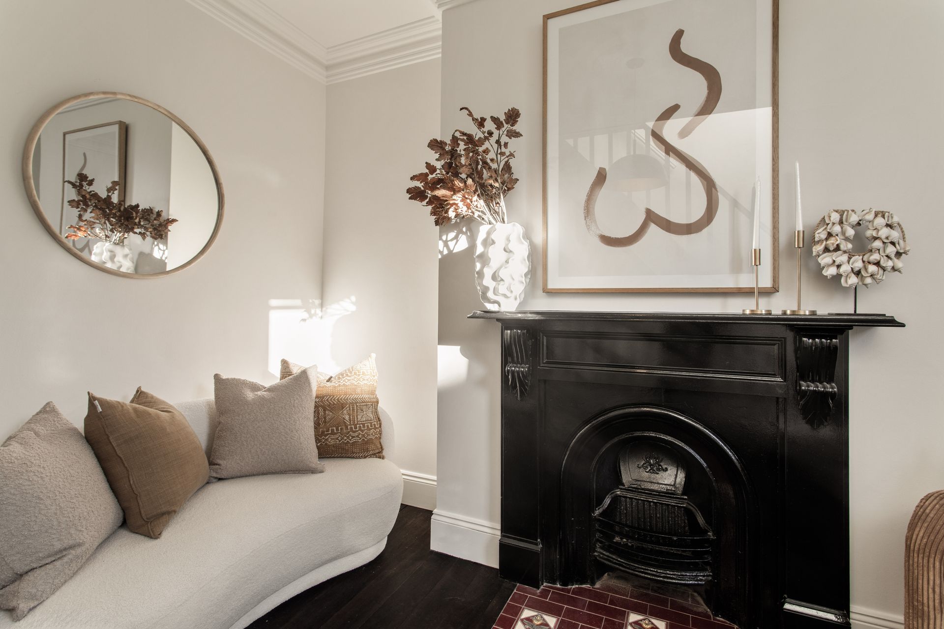 Cozy living room with a white sofa, black fireplace, and neutral decor artwork above the mantel