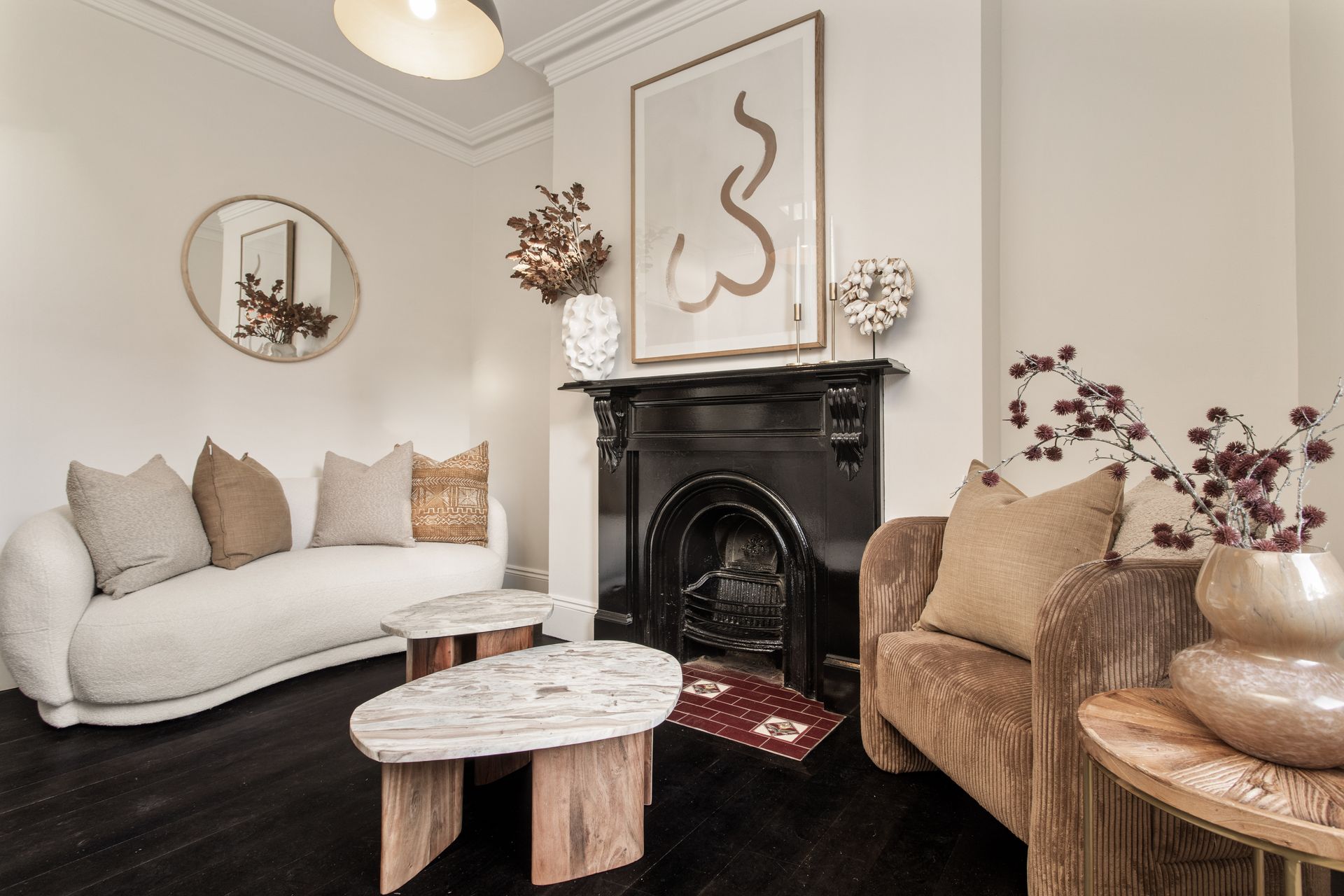 Elegant cream-and-beige living room with black fireplace, sofa, armchair, and round coffee table