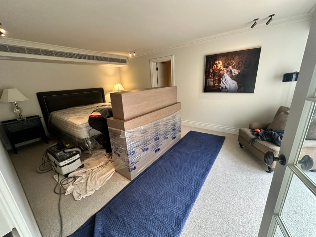 Bedroom interior with bed, dresser, blue rug, lamp, and wall art beside a sliding glass door