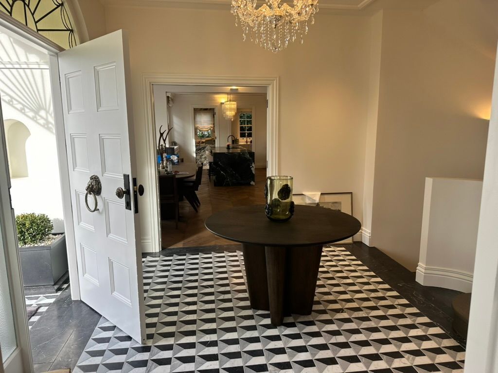 Entryway with open front door, black-and-white floor tiles, round table, and chandelier