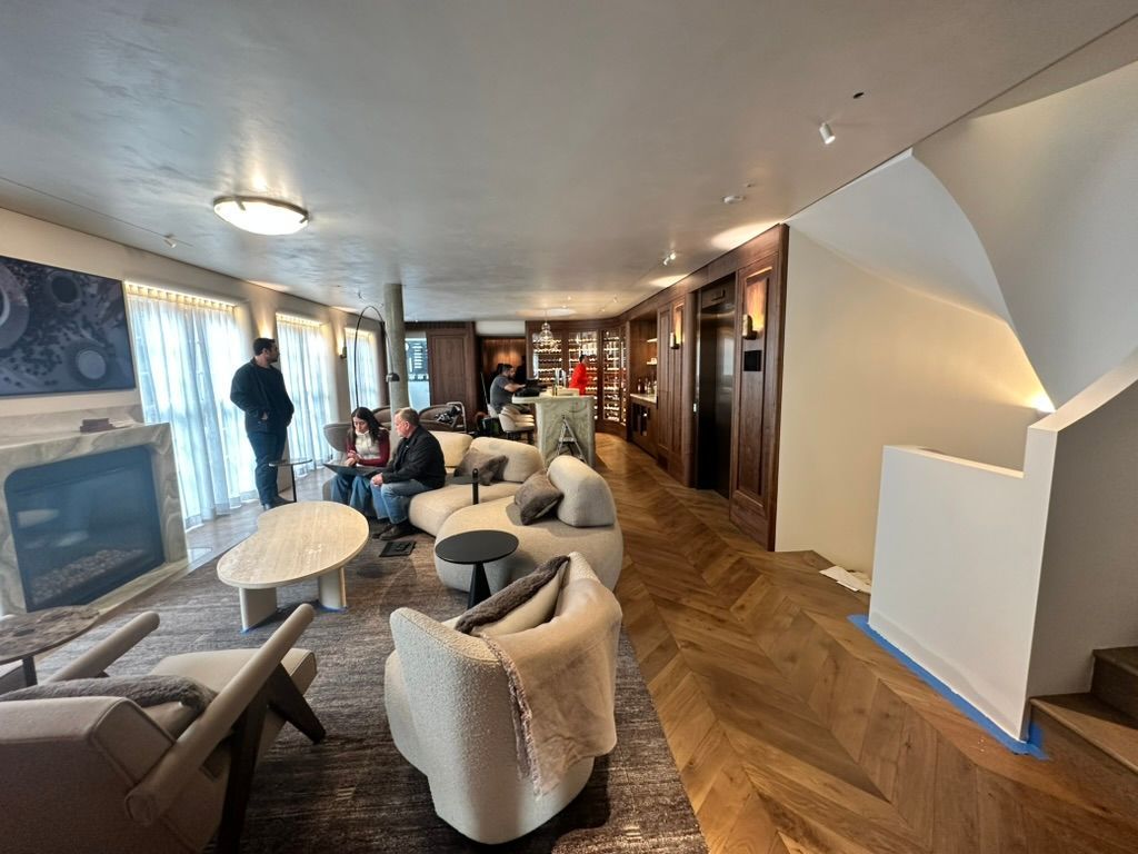 Hotel lounge with curved chairs, fireplace, and two people near large windows