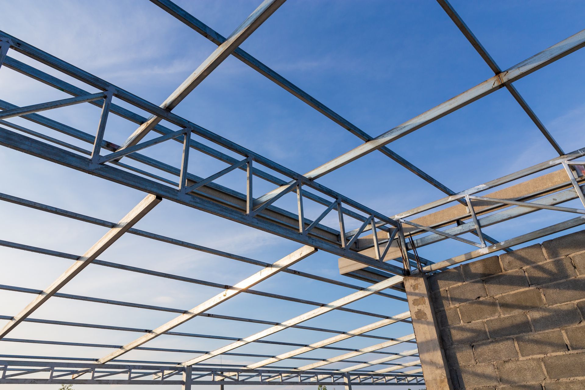 Steel roof trusses against a blue sky above a partially built structure