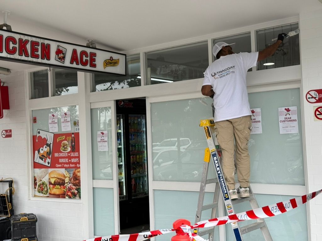 Worker on ladder repairing storefront windows behind red-and-white caution tape Worker on ladder repairing storefront windows behind red-and-white caution tape