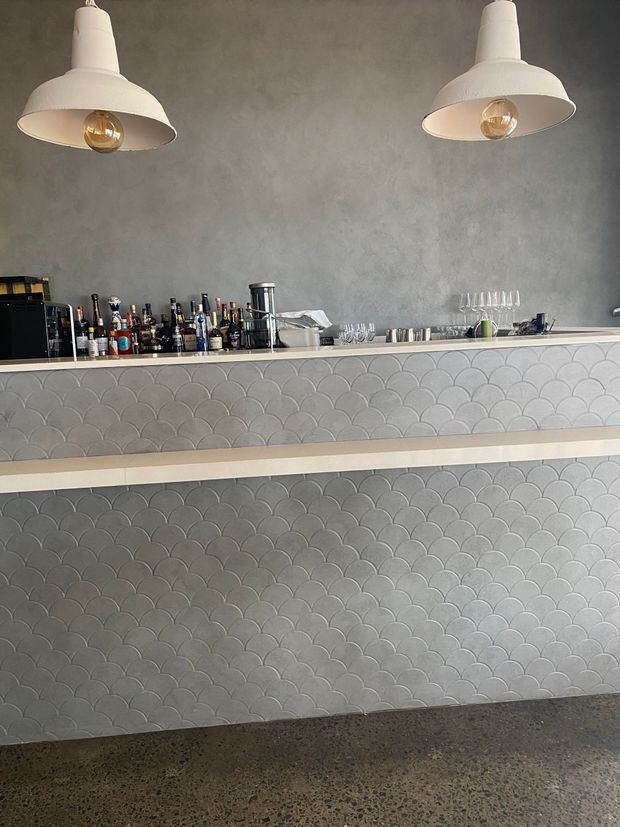 Empty café counter with two hanging white lamps and a patterned gray front.