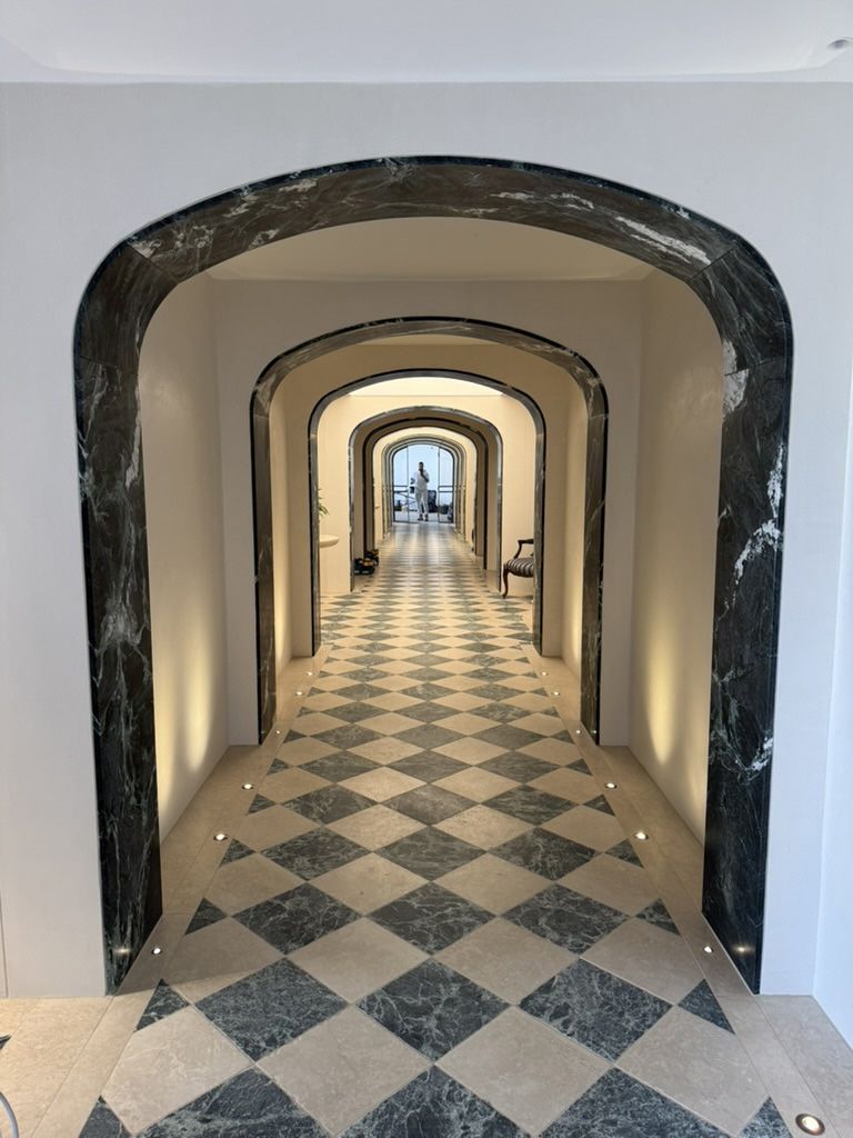 Long arched hallway with black-and-white checkered floor and windows at the far end