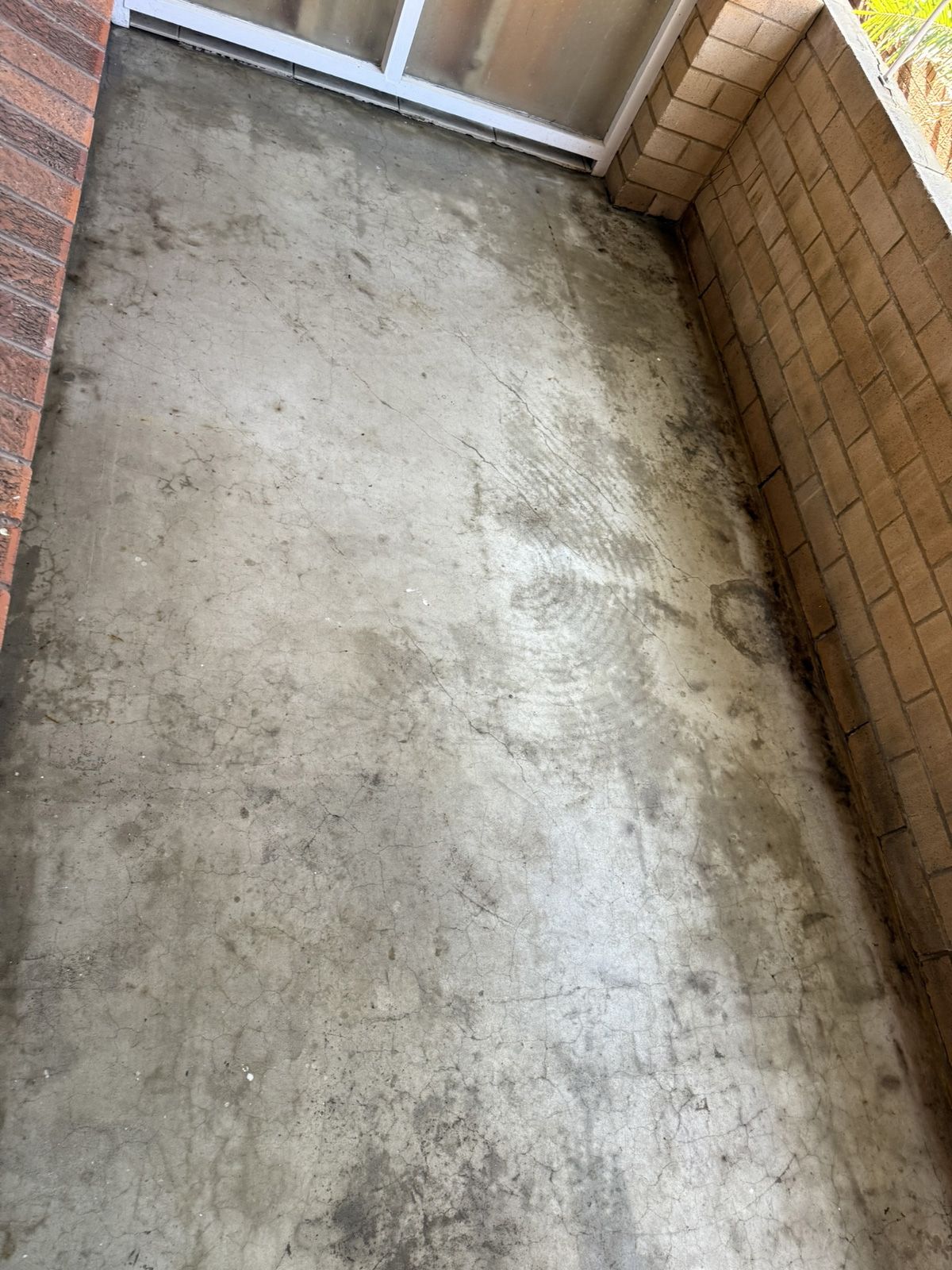 Narrow concrete balcony or corridor with brick walls and a worn, stained floor Narrow concrete balcony or corridor with brick walls and a worn, stained floor