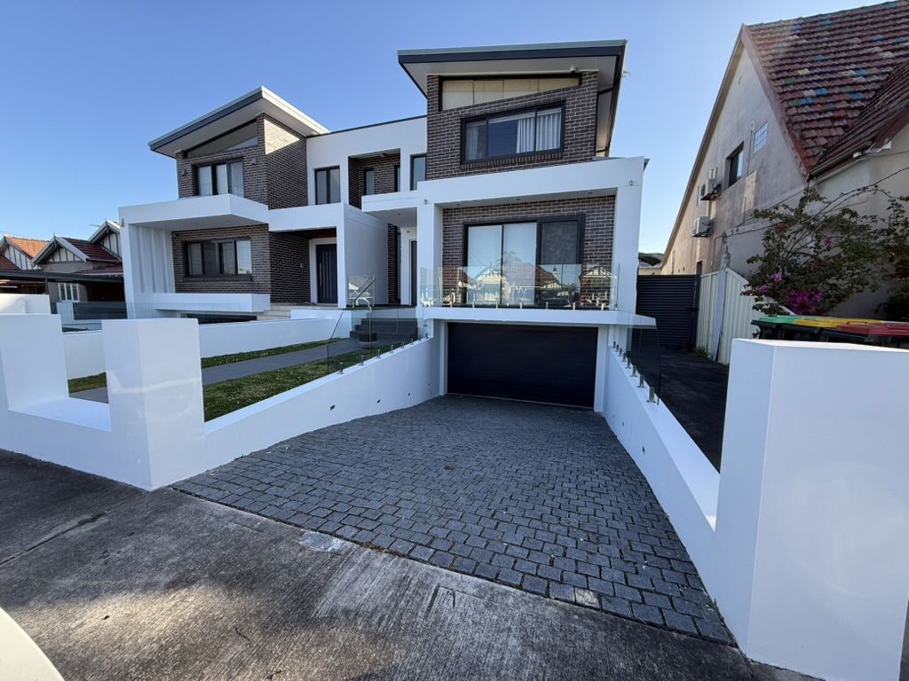 Modern white two-story house with a cobblestone driveway and a covered garage entrance Modern white two-story house with a cobblestone driveway and a covered garage entrance