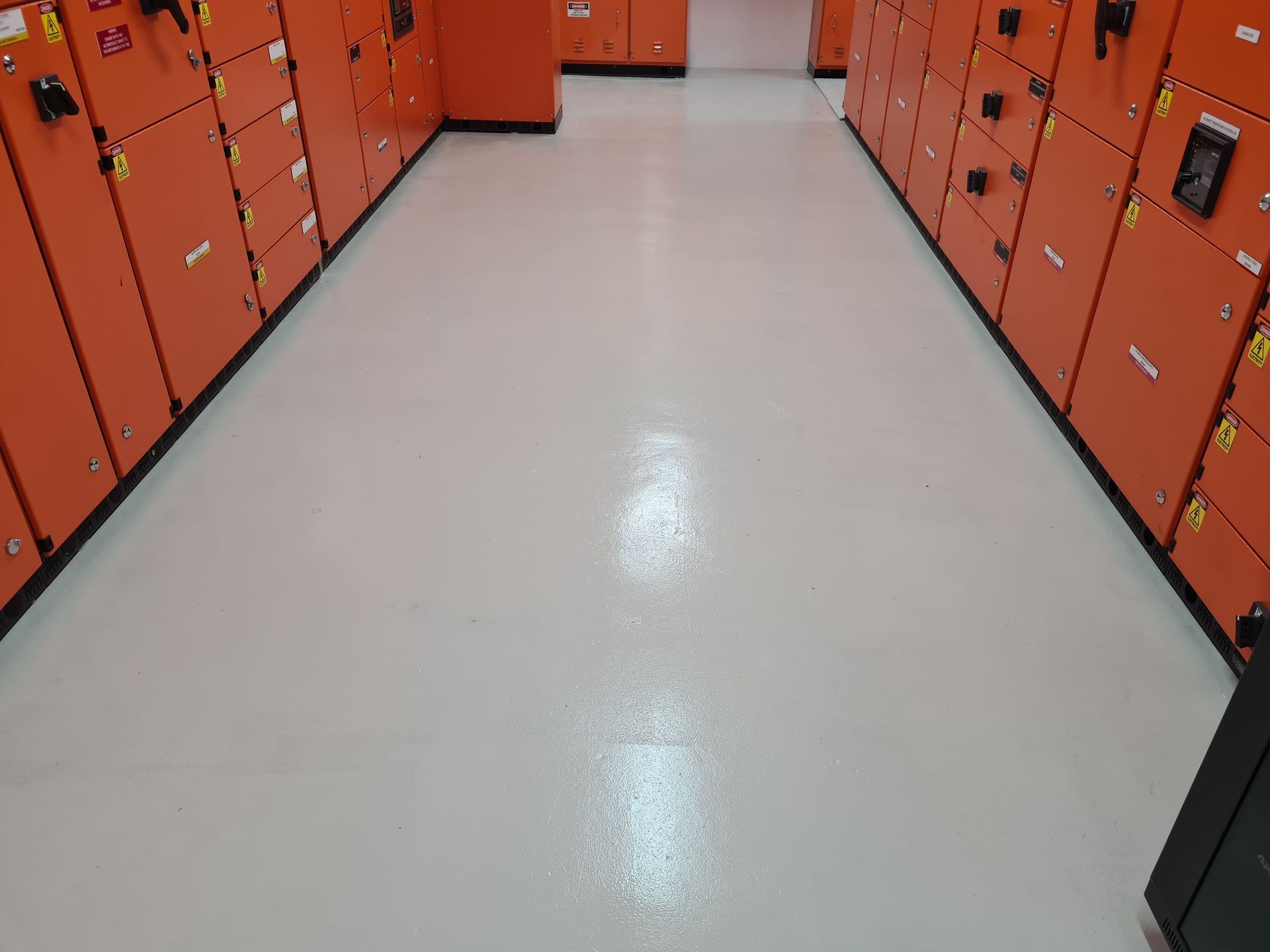 Empty locker room with orange lockers lining both sides and a light gray floor. Empty locker room with orange lockers lining both sides and a light gray floor.