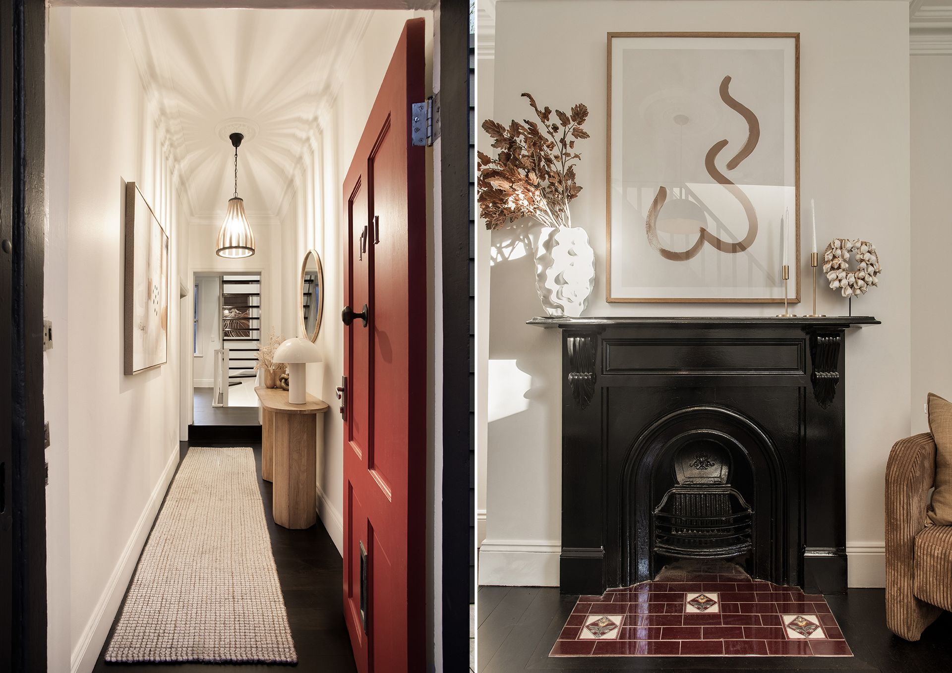 Hallway with red front door, runner rug, and black fireplace beneath framed abstract art