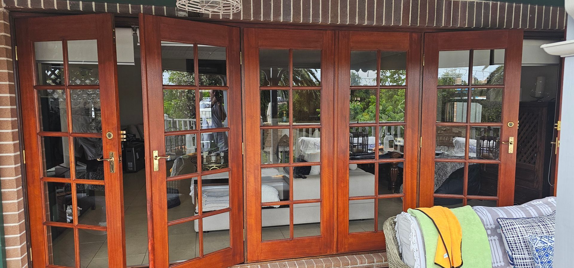 Wooden glass double doors with reflections, beside a couch with a colorful blanket