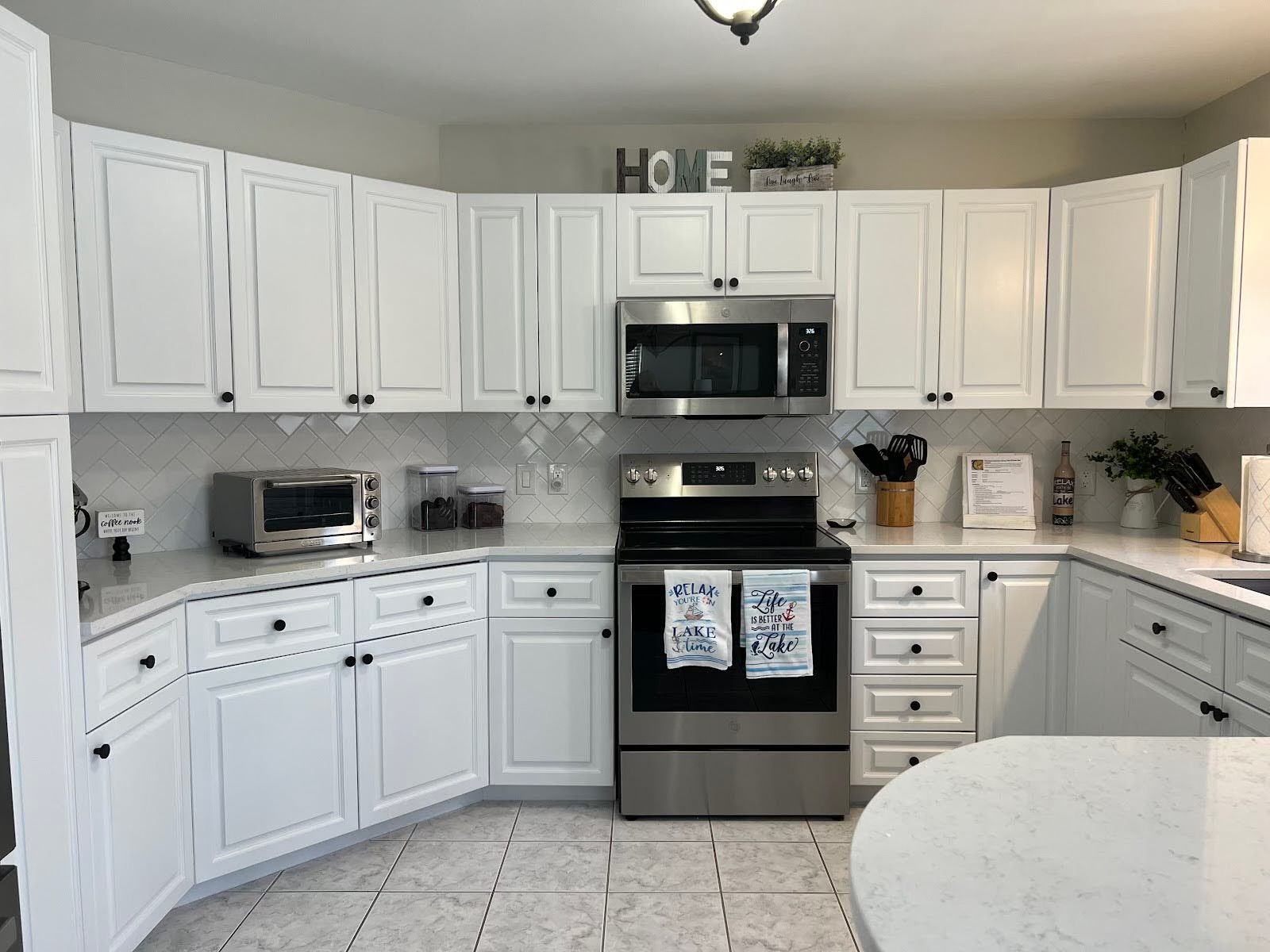 Bright white kitchen with black appliances, U-shaped cabinets, and a light countertop.