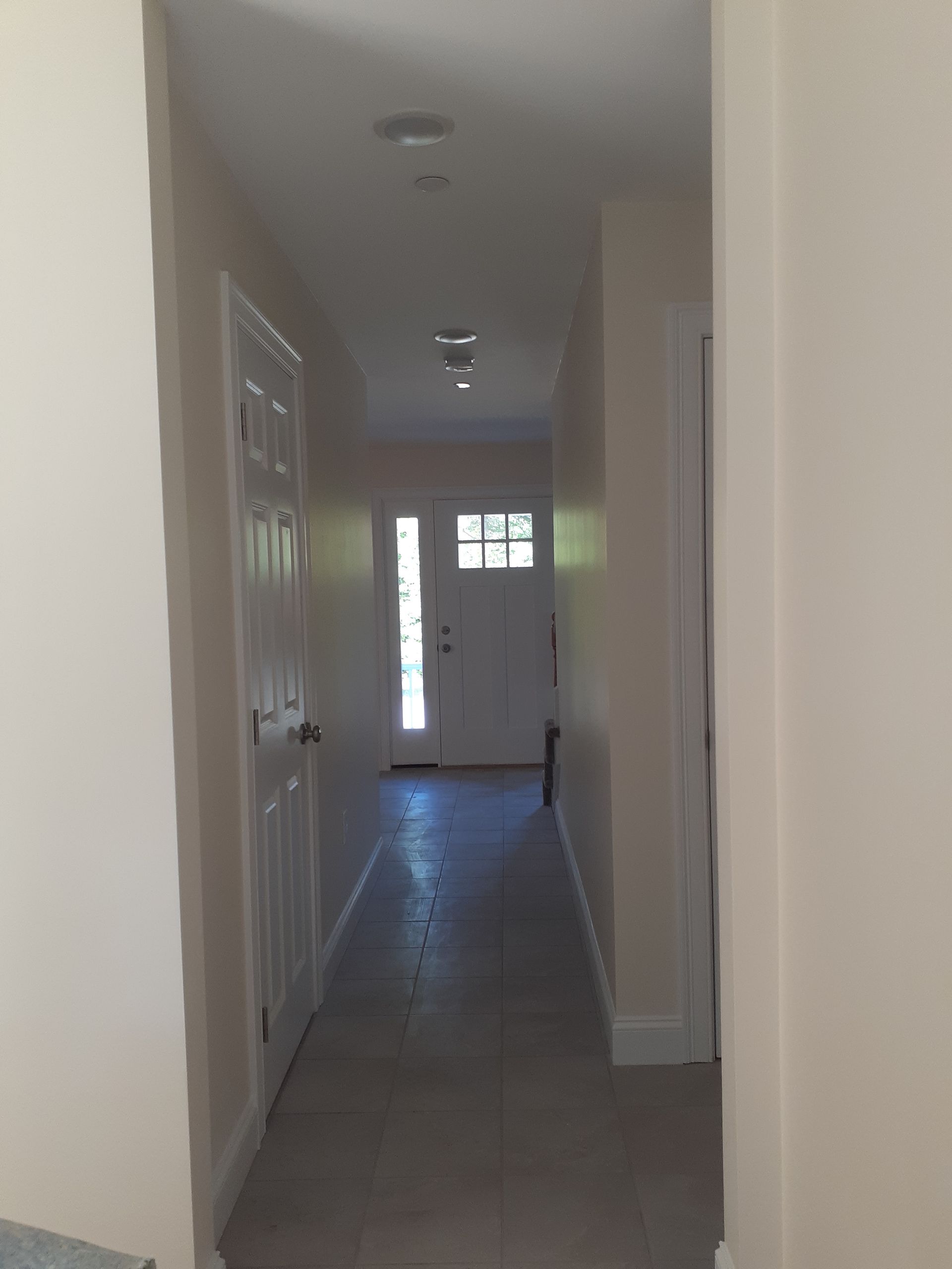A long hallway leading to a door in a house.