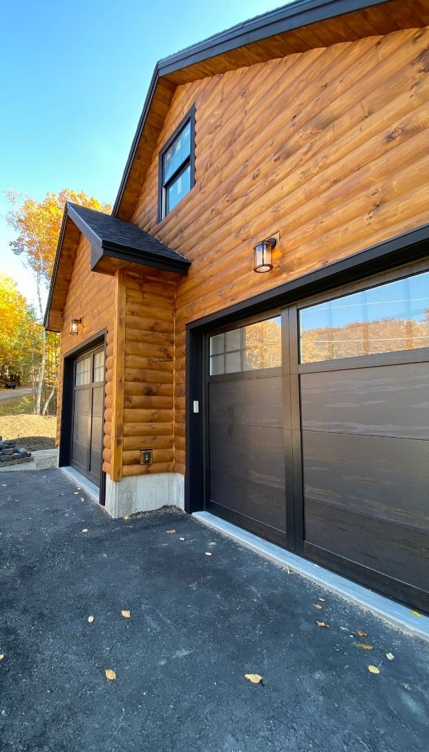 A wooden house with two garage doors and a driveway.