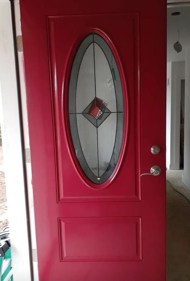 A red door with a stained glass window is sitting in a hallway.