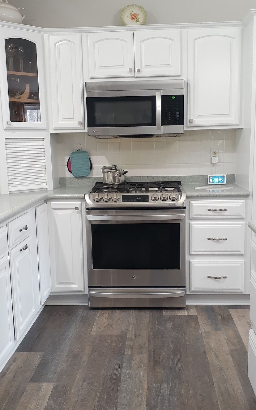 A kitchen with blue walls , white cabinets , granite counter tops and a window.