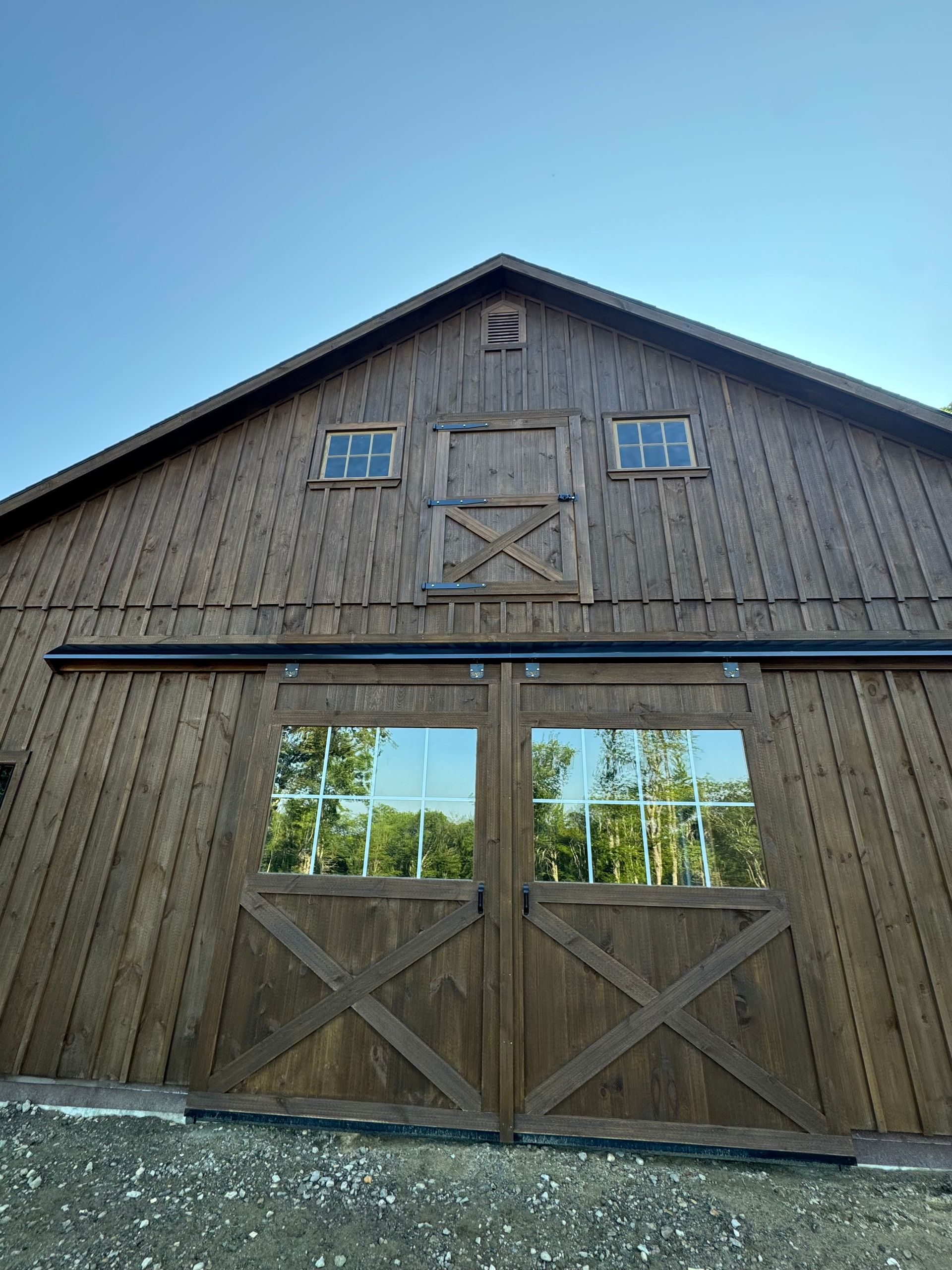 Rustic wooden barn with large sliding doors under a clear blue sky.