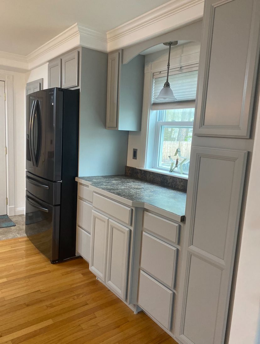 Kitchen with white cabinets, black refrigerator, granite countertop, and a window above the sink.