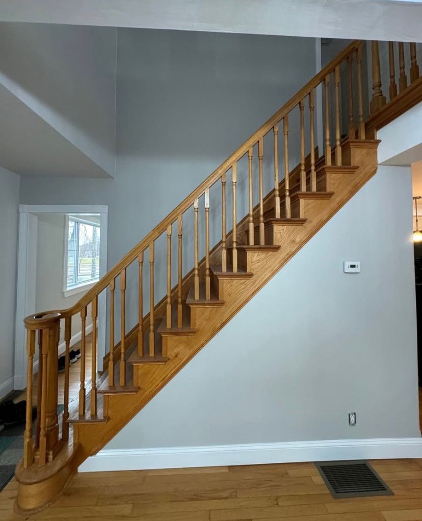 Wooden staircase with railing in a gray-walled interior hallway