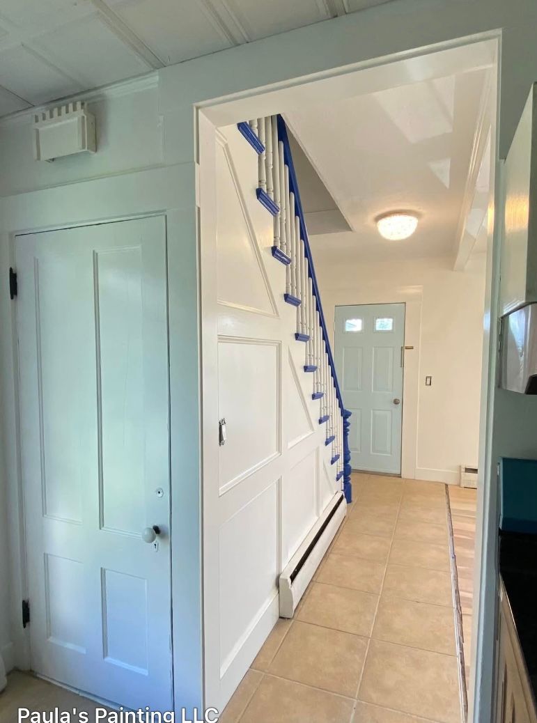 Hallway with light blue walls, white staircase under construction, and a closed door on the left.