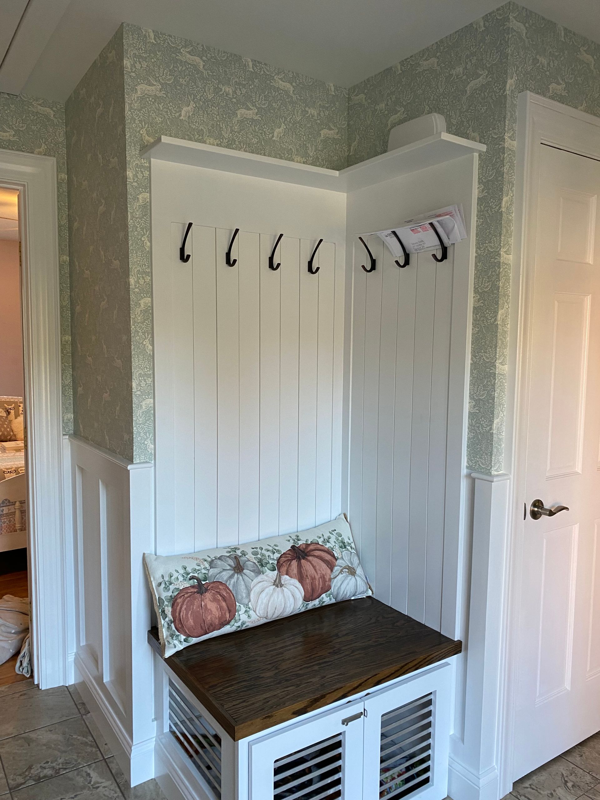 A hallway with a bench and hooks on the wall