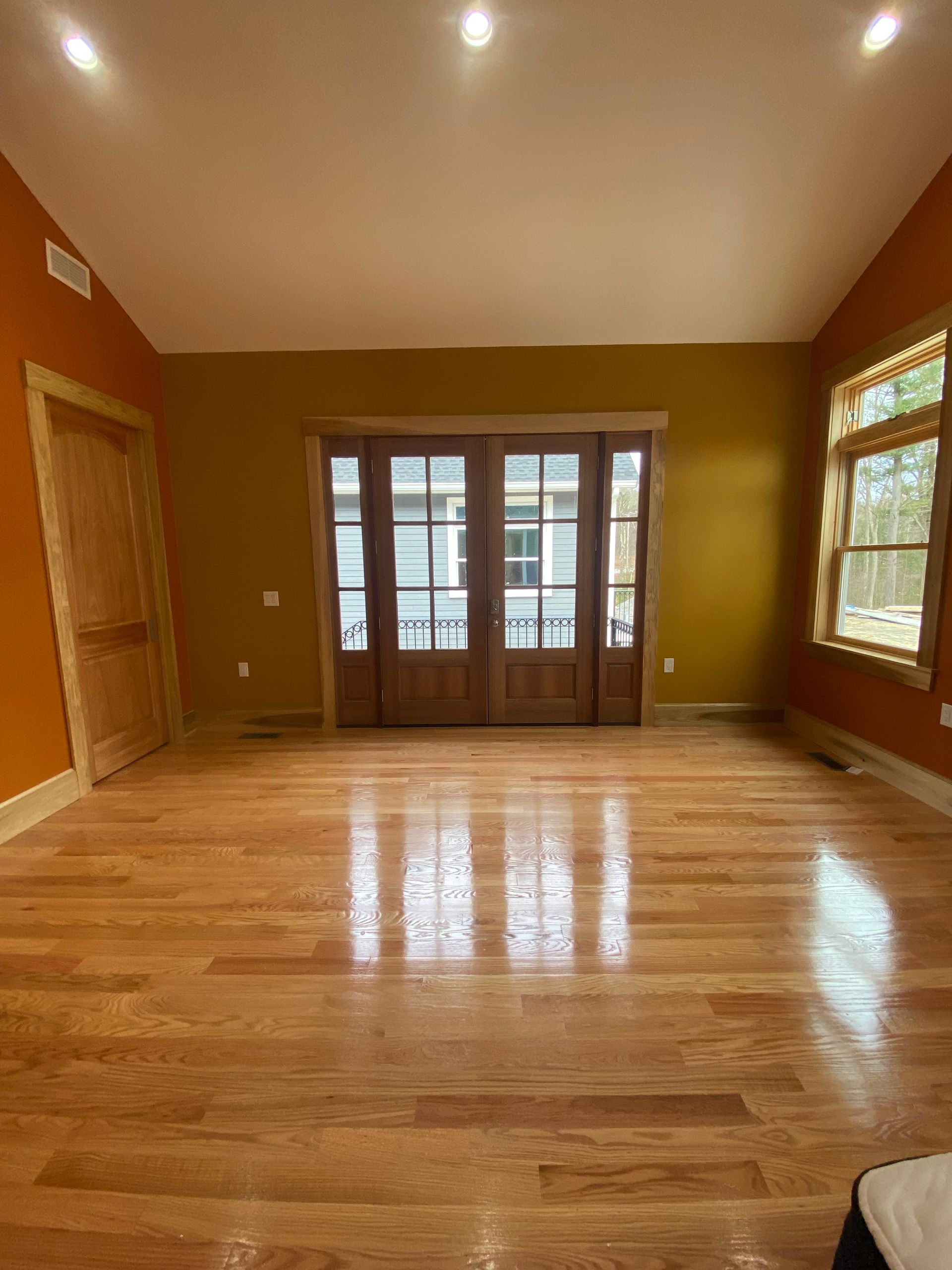 An empty living room with hardwood floors and yellow walls.