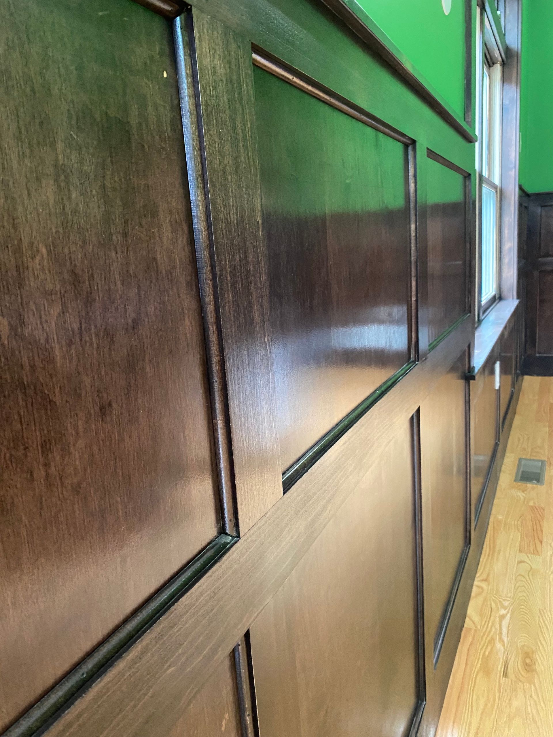 A long hallway with wood paneling and a window.