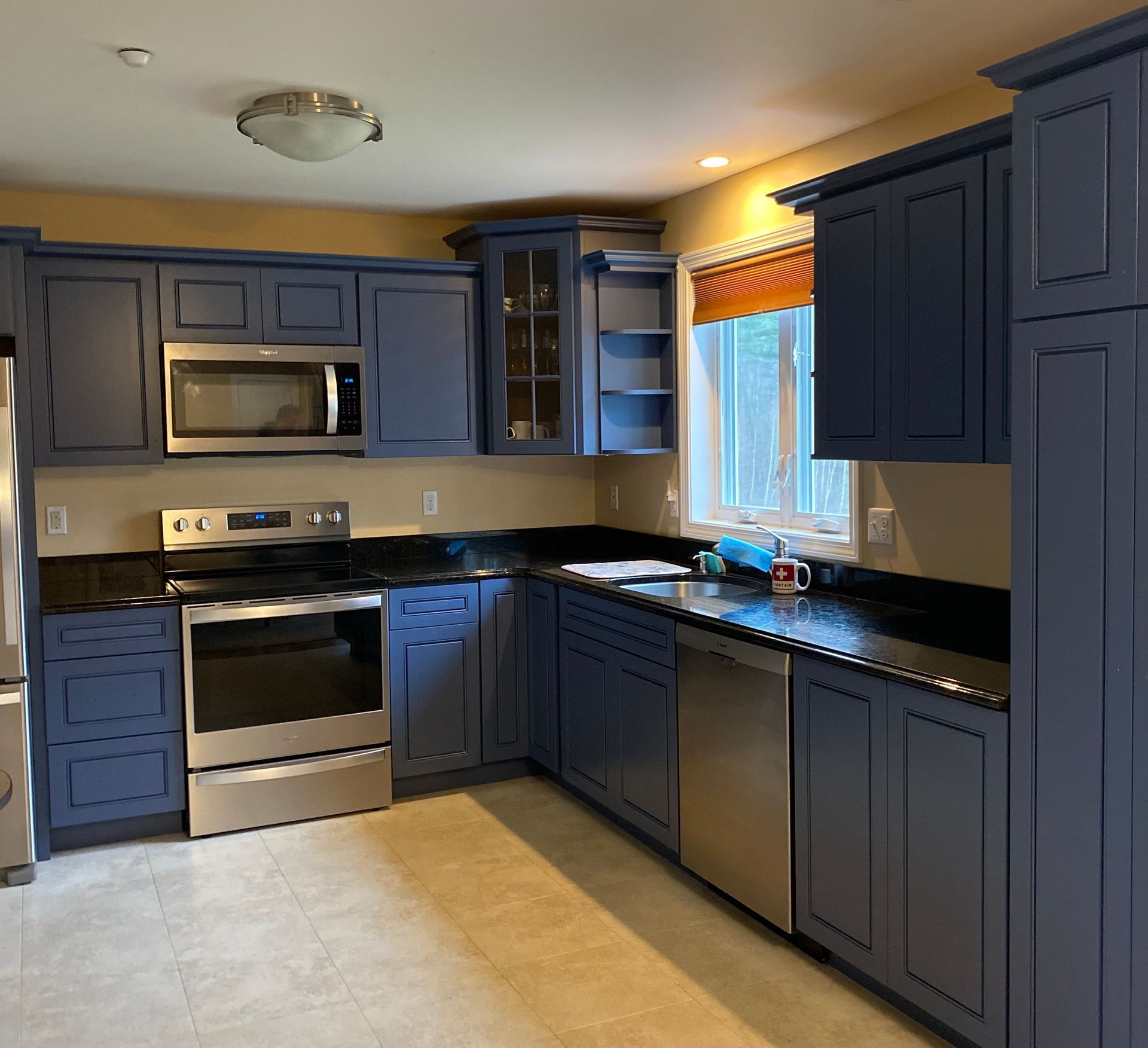 A kitchen with white cabinets and a marble counter top.