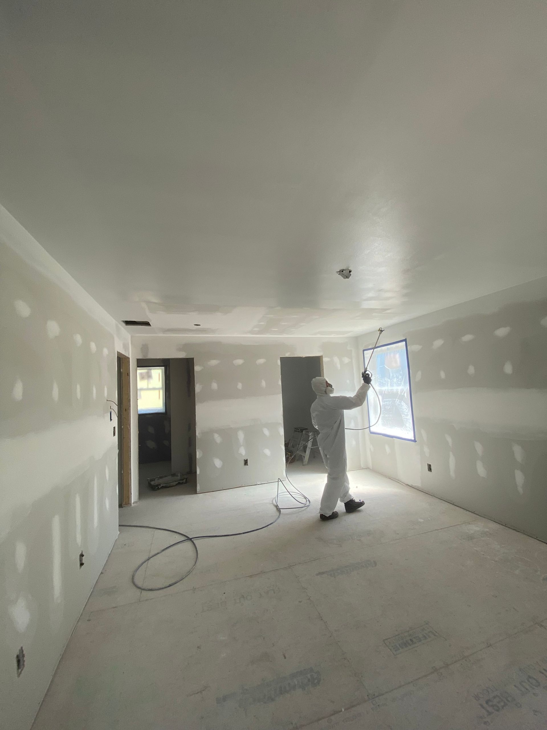 A man is spraying paint on a wall in a room.