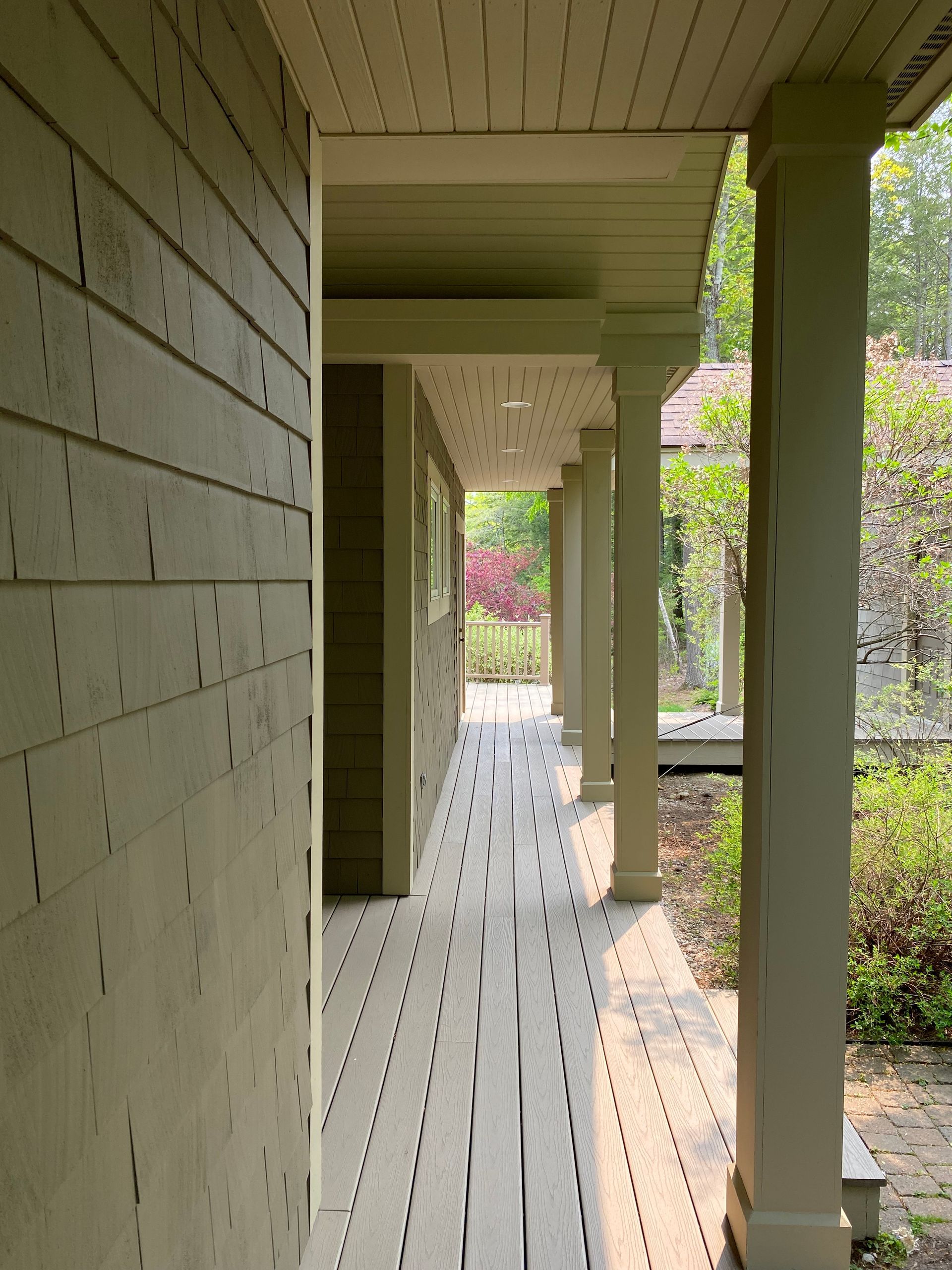 A wooden walkway between two houses with trees in the background