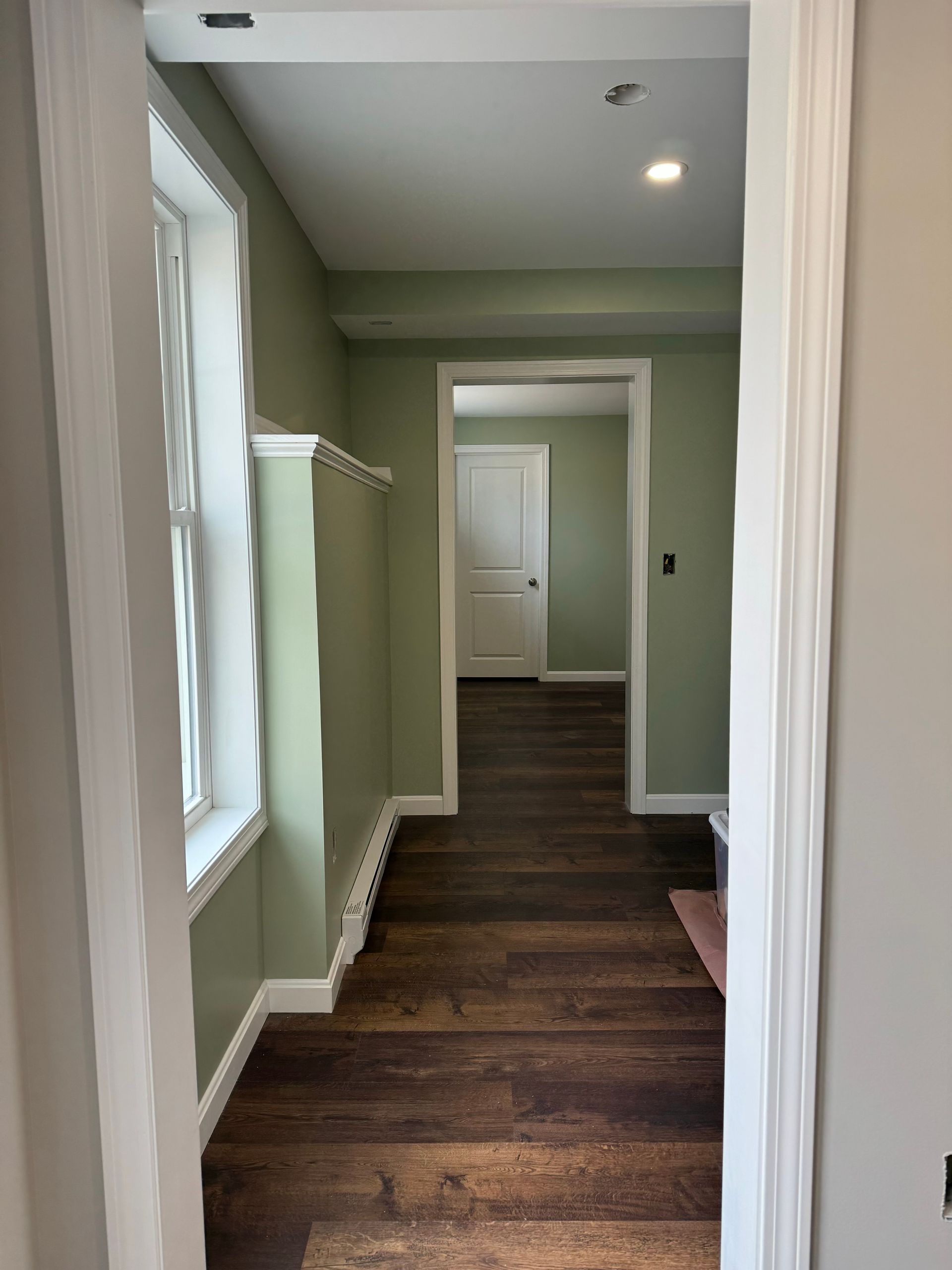 A hallway with wooden floors and a window in a house.