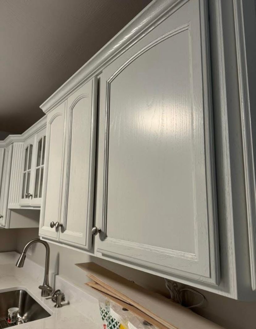White kitchen cabinets with decorative trim above a countertop and sink area