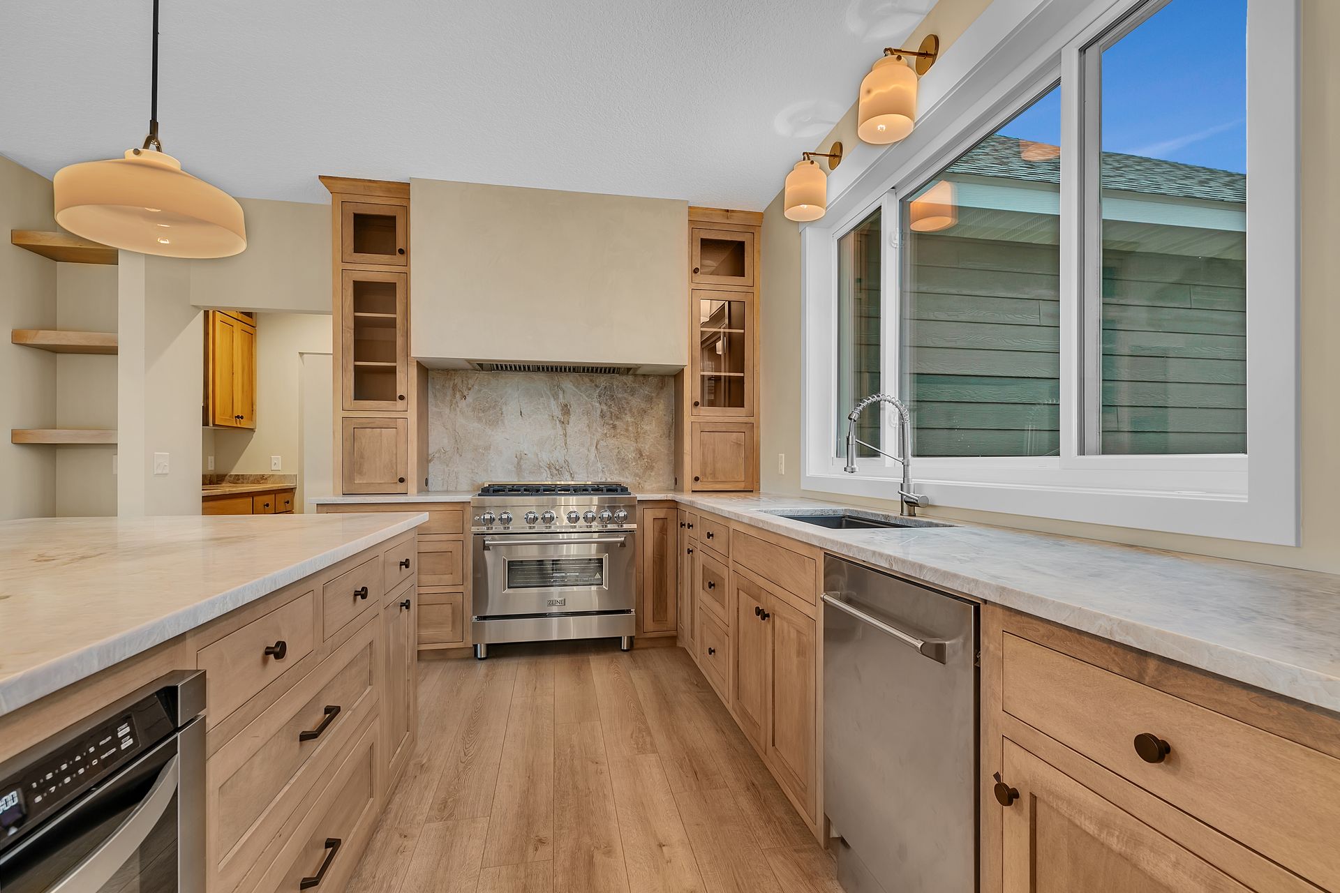 A kitchen with wooden cabinets , stainless steel appliances and a large window.