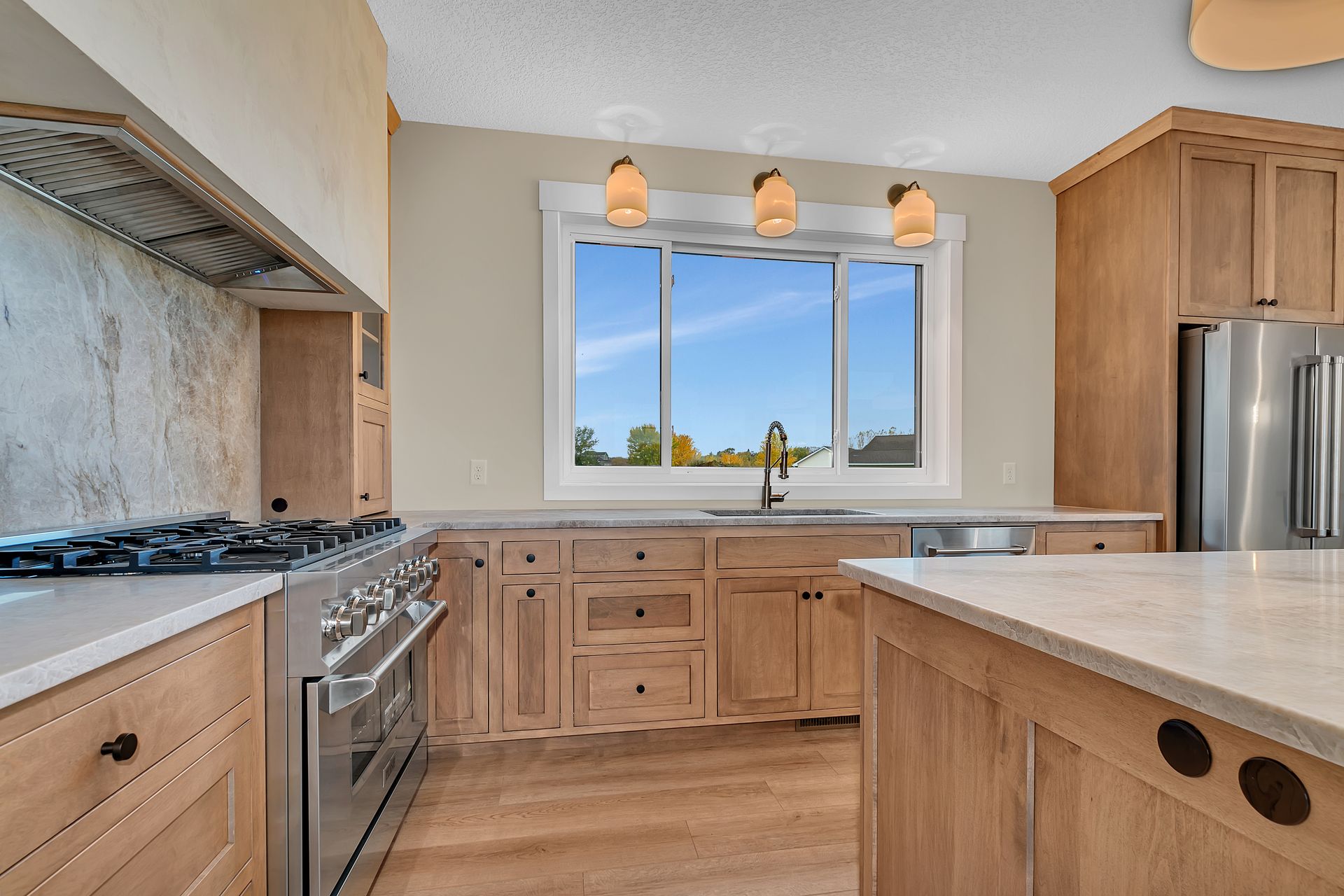 A kitchen with wooden cabinets , stainless steel appliances , and a large window.