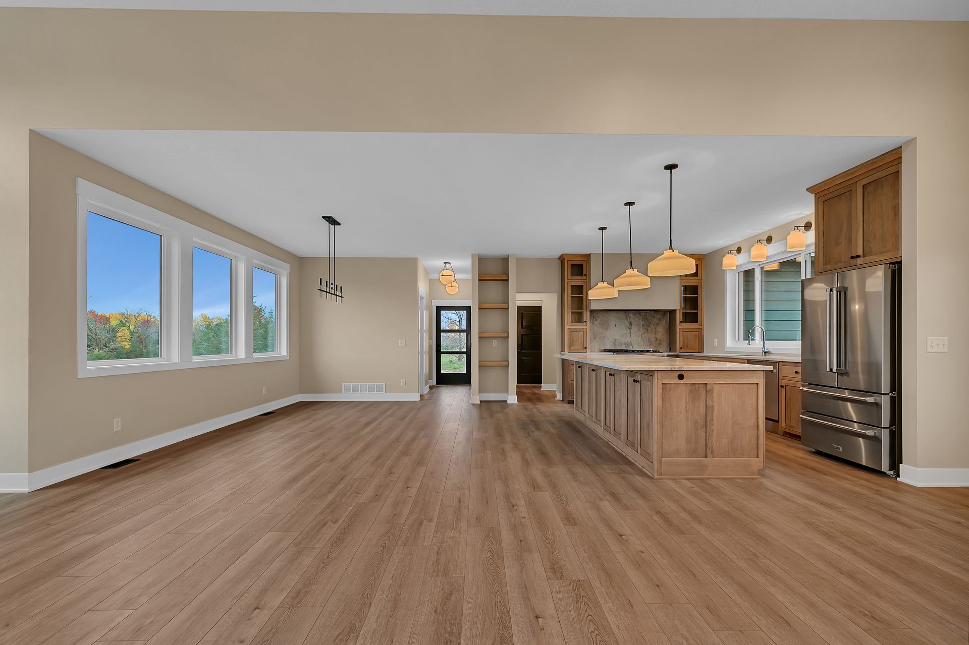 A large empty kitchen with hardwood floors and stainless steel appliances.