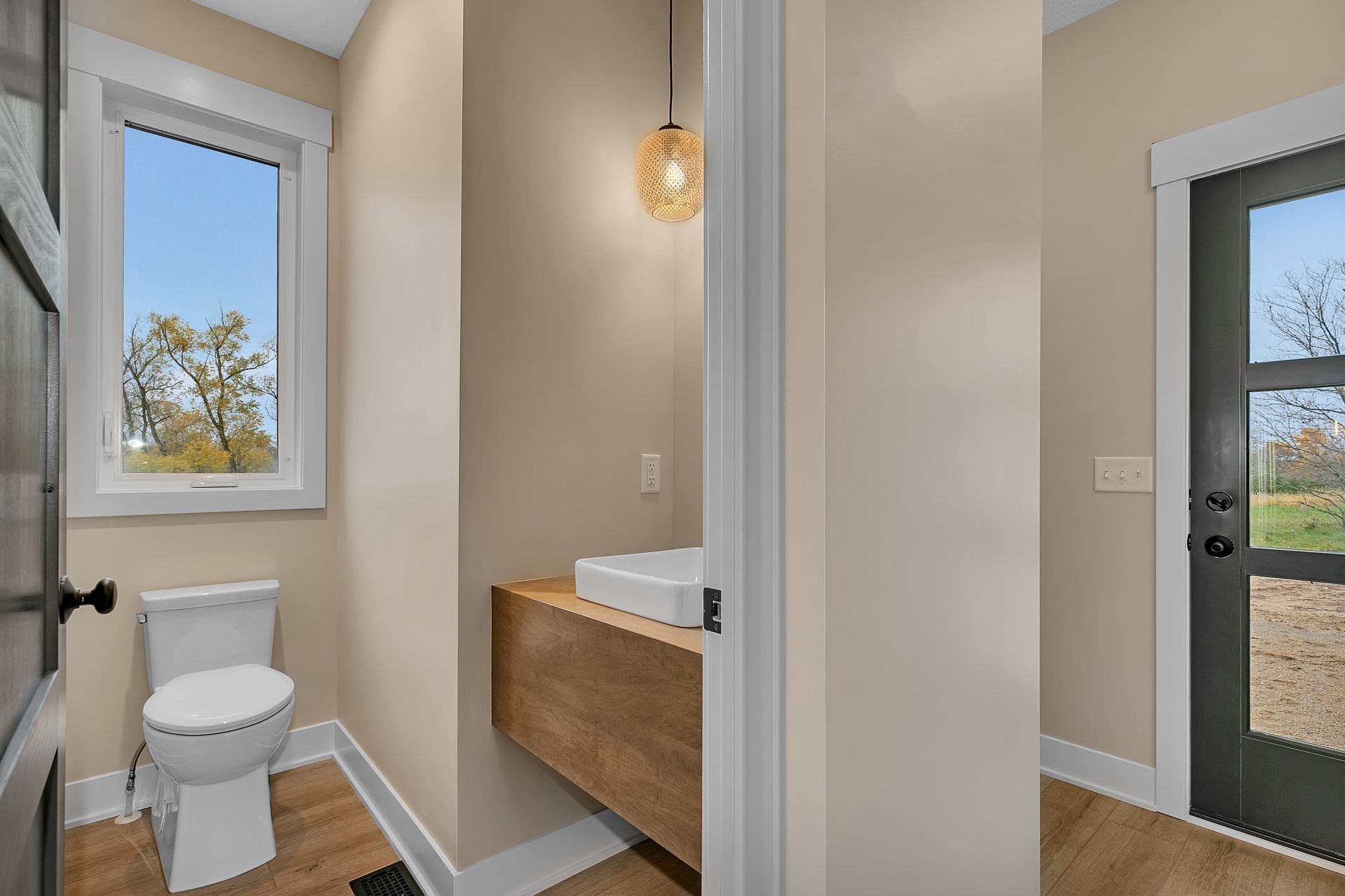 A bathroom with a toilet , sink and window.